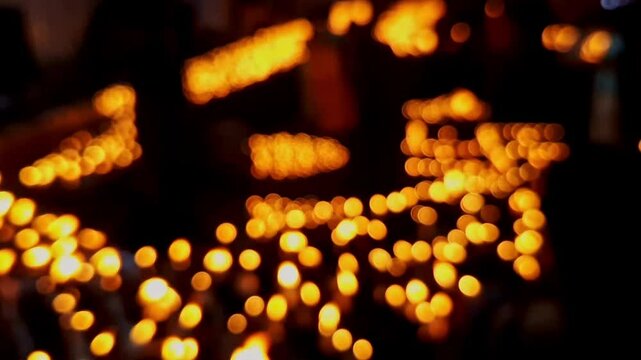 A cinematic transition video of blurry, glowing candles or diyas at a temple during the night