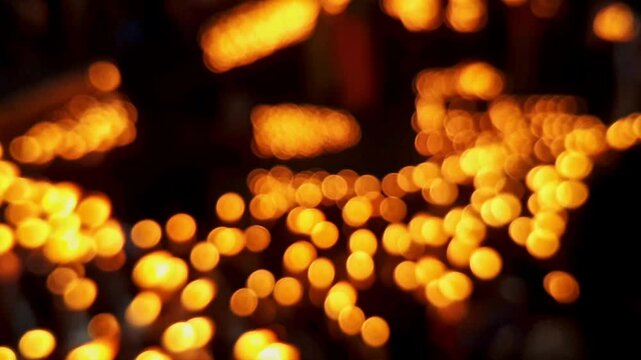 A cinematic transition video of blurry, glowing candles or diyas at a temple during the night