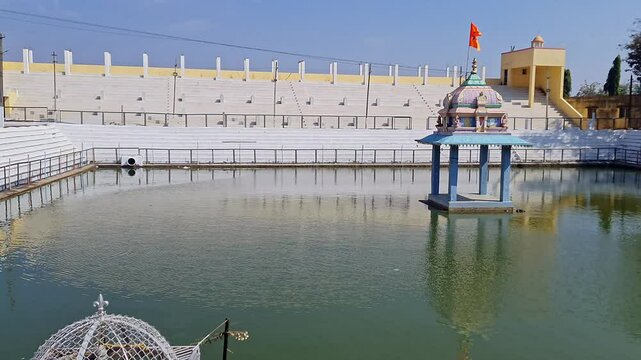 A pan video of a small temple amidst a Pushkarani or Kalyani pond with an intricate stepped design