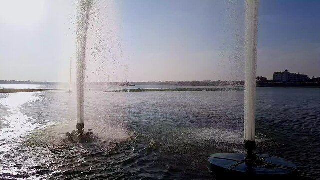 A video of water fountains or jets in a reservoir, pumping water high into the sky during dusk