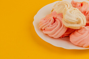 Colorful meringue cookies on a bright yellow plate