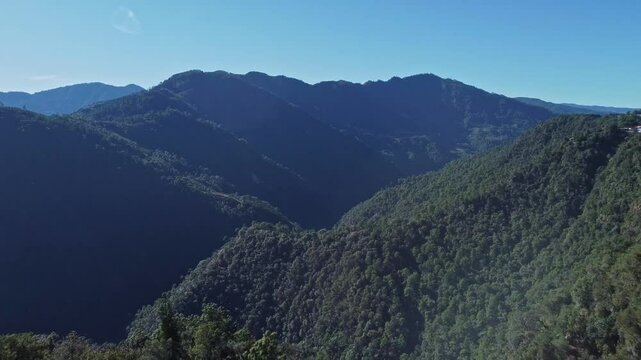 Drone pull back shot of mountains and forest with a town located at cliff in rural Mexico.