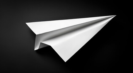 A white paper airplane against a dark background.  A meticulously folded paper airplane, with crisp angles and folds, sits poised in mid-air against a completely black backdrop.