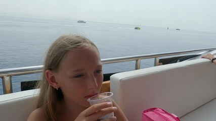 Youthful woman lounging on luxurious yacht, sipping refreshing beverage while gazing across tranquil ocean horizon during serene summer maritime getaway