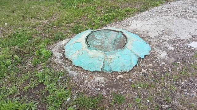 An old sewer manhole with a metal lid in close-up. The concept of plumbing system repair. An accident on the heating main. 