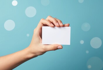 Obraz premium A hand holds a blank white card against a blue background with soft circular light effects