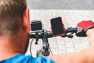 Smartphone and action camera on the handlebars of a bicycle. A man rides a bicycle.