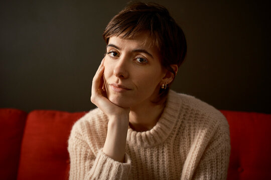 Woman sitting on a couch in London, looking at the camera with a concerned expression