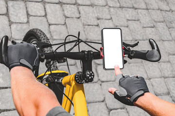 Close-up of a finger in front of a smartphone mockup on a bicycle handlebar. Background of gray...