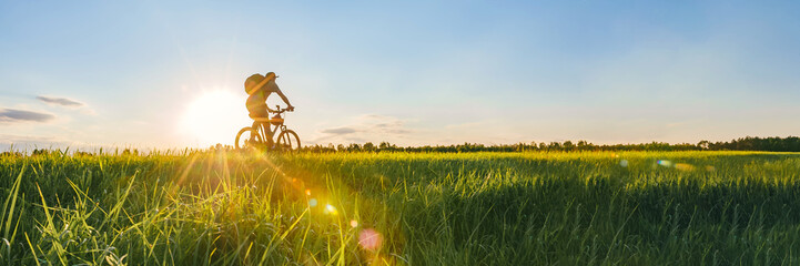 Long Banner, Cyclist riding a bike in a field.