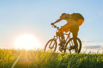 Fototapeta premium Rear view. Cyclist riding a bike in a field.