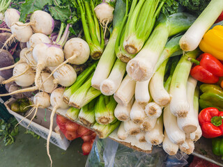 Assortment of fresh vegetables and greens on farmers market stall close up.