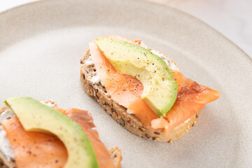 Close-up of healthy toast with avocado, salmon and cream cheese on whole grain bread. Balanced and natural eating. Concept of healthy breakfast
