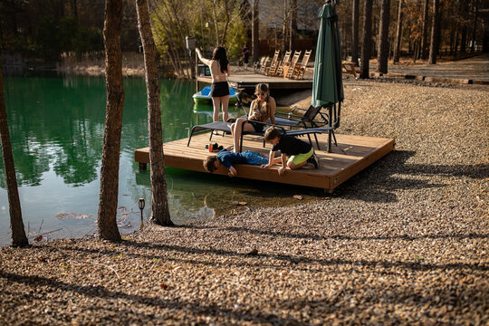 siblings fishing and sunbathing on wooden dock in golden sun