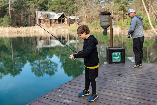 father and son fishing on a dock near a lakefront cabin