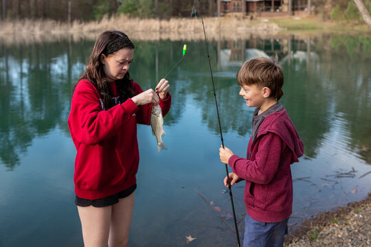 siblings fishing at a lake near a cabin in the woods