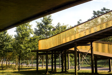 Fototapeta premium yellow pedestrian bridge in the middle of green park background 
