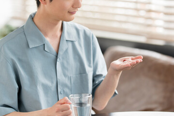 薬（サプリメント）を飲む若いアジア人男性