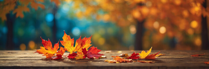 Colorful autumn leaves rest on a wooden table with a blurred forest background, creating a warm scene.