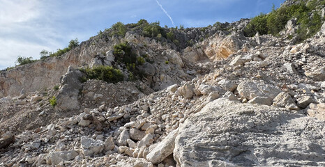 Rocky hillside with scattered boulders and vegetation under a clear blue sky