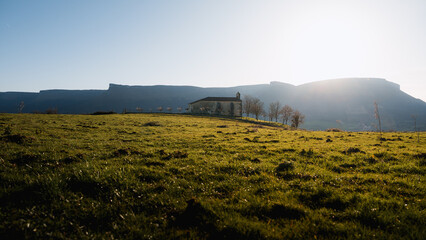 Idyllic basque countryside with chapel and majestic mountain range at sunset
