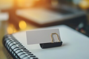 Blank card clipped on a spiral notebook with blurred background in a well-lit workspace setting