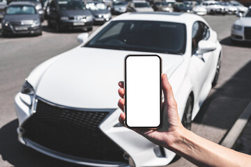 Close-up Mock-up of a smartphone in a woman's hand. Background of auto market. Concept of Buying...