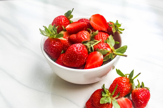 a bowl of strawberries on a ceramic floor as a background