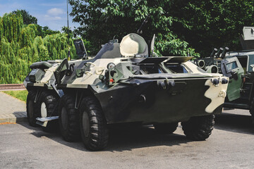 Military vehicle armored personnel carrier with camouflage coloring. Background of nature and trees.