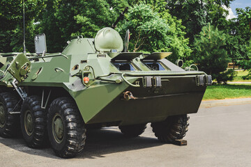 Fototapeta premium Military vehicle armored personnel carrier with camouflage coloring. Background of nature and trees.