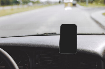 Obraz premium A close-up of a mock-up of a black smartphone screen mounted on the front of a car.