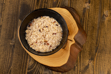 oatmeal porridge with dried berries and fruits in a black bowl , cooking instant oatmeal porridge, closeup, top view