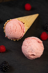 melting ice cream on a black board, sweet cold pink ice cream with strawberry flavor, ice cream in a waffle cone