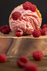 pink sweet raspberry-flavored ice cream lies on a walnut board, ripe red raspberries and raspberry cold natural ice cream on the table