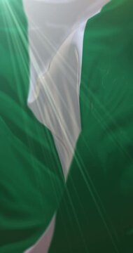 Flag of Nigeria waving at wind in slow in blue sky, loop. 4K Vertical