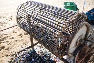 Mussel cleaning cage on sandy beach