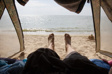 View of feet inside tent at beach