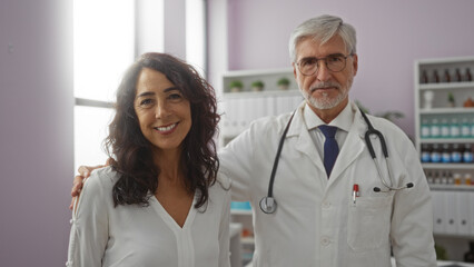 Fototapeta premium Doctor and woman smiling together in a medical clinic, depicting a positive healthcare environment indoors with a focus on patient care and professional interaction.