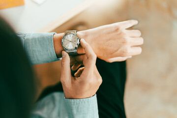 businessman in casual fashion checks his stainless wristwatch is waiting for his next appointment...