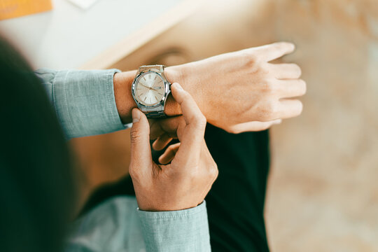 businessman in casual fashion checks his stainless wristwatch is waiting for his next appointment focused on time cooperation and consulting, top view above. - Powered by Adobe