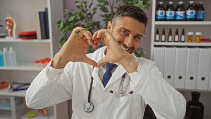 Smiling doctor making heart shape with hands in a bright clinic interior showcasing friendly...