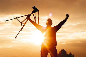 Victorious Photographer Silhouette Winning at Sunset with Tripod Camera