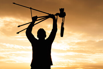 Silhouette of Man Holding Tripod and Camera at Sunset.