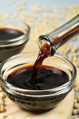 Close-up of the process of pouring soy sauce into a saucepan.