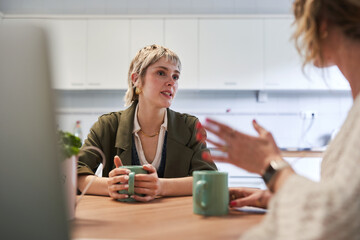 Women having a coffee conversation in a modern office kitchen