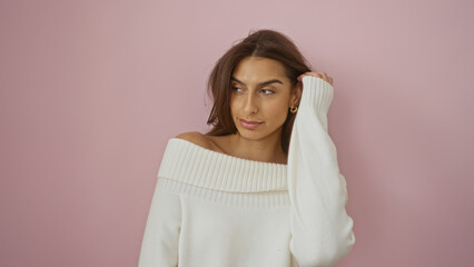 Fototapeta premium Woman wearing white sweater poses against pink background, highlighting her beauty and brunette hair, showcasing a casual yet elegant fashion style.