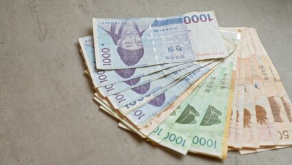 South korean banknotes spread out on a concrete surface highlighting various denominations of the won currency.