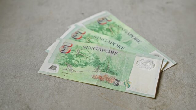 Close-up of singapore five-dollar banknotes on a concrete surface showcasing currency details and asian financial elements in a neutral setting
