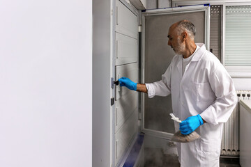 Scientist storing biological sample in laboratory ultra-low temperature freezer