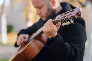 Musician playing acoustic guitar outdoors in park